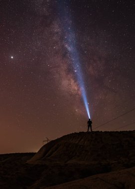 Samanyolu gece gökyüzünde ve elinde fenerle ayakta duran adam silueti. Renkli gece manzarası. Evreni keşfediyorum.