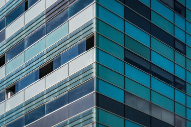 Mavimsi ve yeşilimsi pencereleri olan bir konut binasının köşesinin simetrik görüntüsü