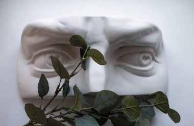 Beyaz arka planda yeşil yapraklı beyaz insan heykeli