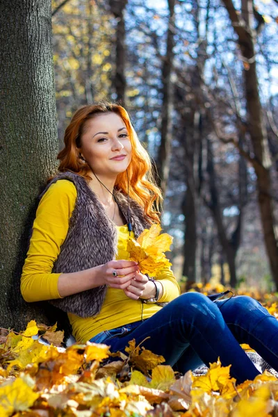 年轻的漂亮女人在公园里听音乐在秋天 — 图库照片
