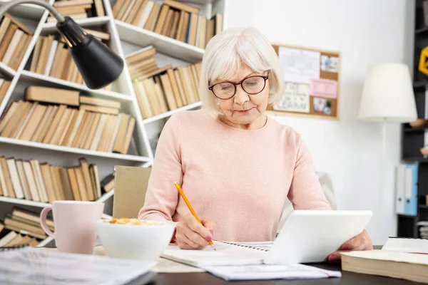 Earnest senior woman taking notes — Stock Photo, Image