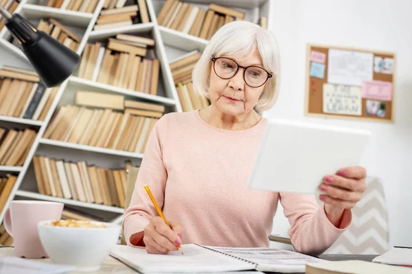 Careful senior woman watching lecture — Stock Photo, Image