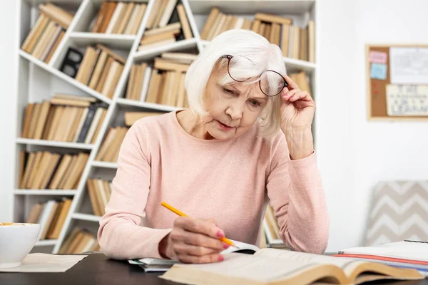 Attentive senior woman having trouble in study — Stock Photo, Image