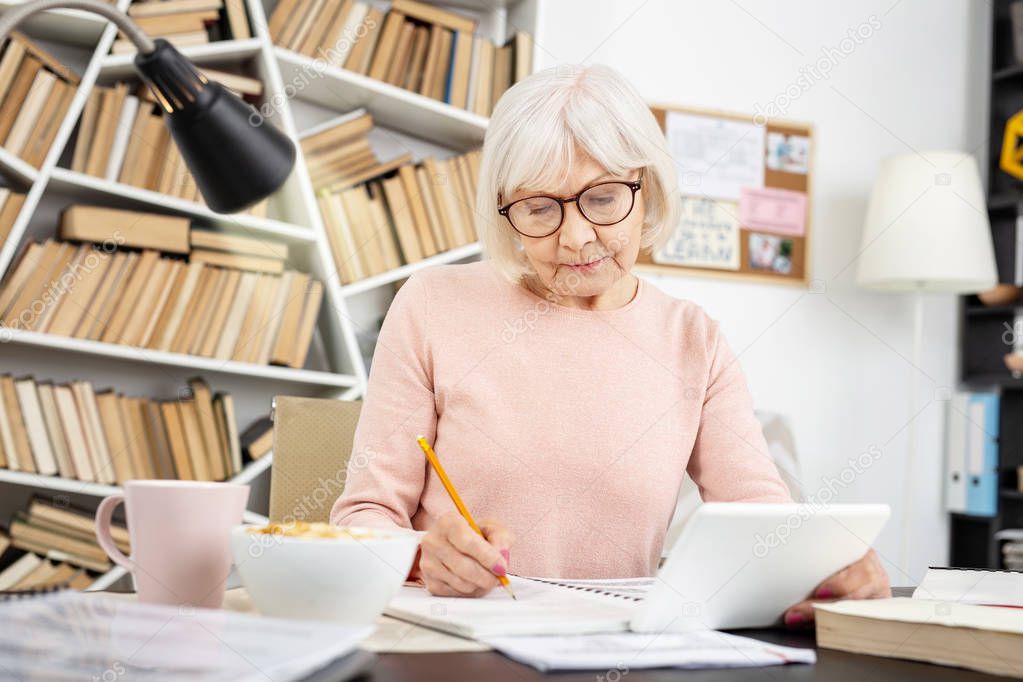 Earnest senior woman taking notes