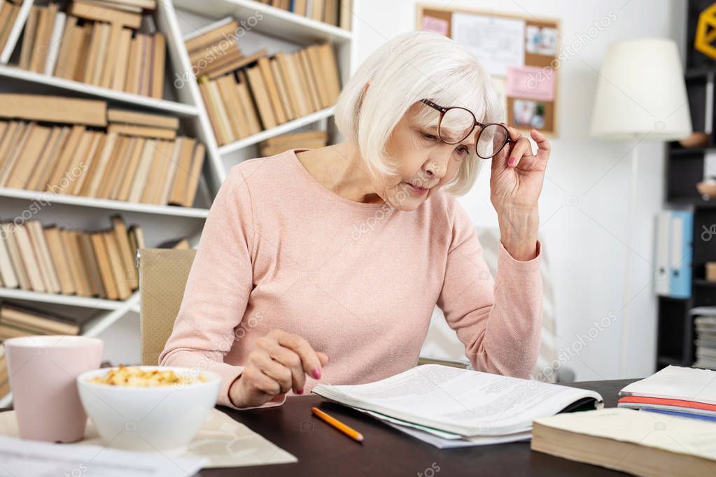 Focused senior woman reading task