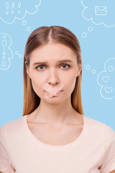 Sad woman having a sticking plaster on her lips and looking miserable — Stock Photo, Image