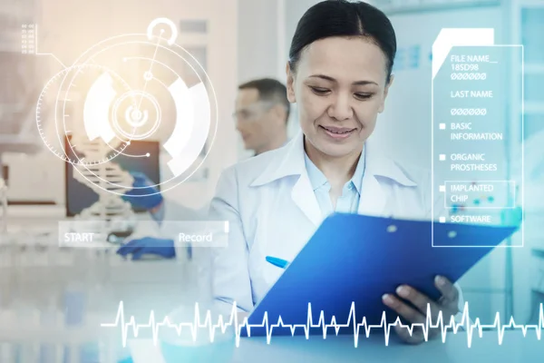 Alegre médico sonriendo y tomando notas en un portapapeles —  Fotos de Stock