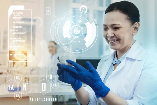 Científico alegre mirando la miniatura del corazón y sonriendo — Foto de Stock