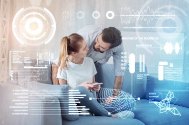 Genç kadın bir smartphone ve onun erkek arkadaşı ona yaslanmış oturuyor