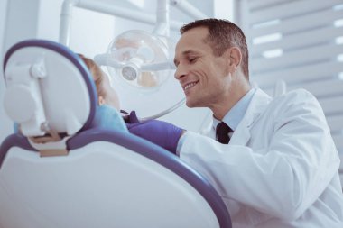 Ağız sağlığı. Sırıtarak ise diş enstrüman kullanarak neşeli erkek diş hekimi