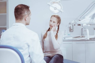 Diş sorunu. Kasvetli özenli kız erkek dişçide bakarken yanak dokunmadan