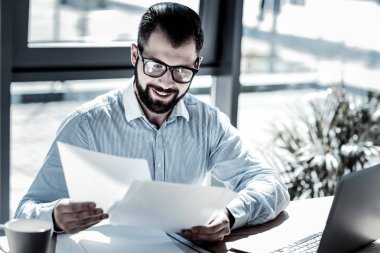 Oturma ve belgeleri bakan memnun gözlüklü adam.