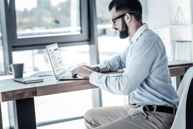 Oturma ve dizüstü bilgisayar kullanarak işgal sorumlu çalışan.