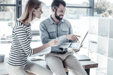 Gülümseyen ve dizüstü bilgisayar kullanarak ilginizi meşgul arkadaşları.