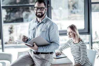 Klasörü tutarak ve gülümseyen memnun işgal altındaki adam.