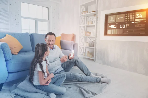 Calm father holding a remote control and talking to his attentive child