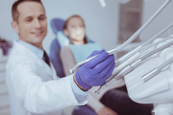 Positive male dentist selecting dental tool — Stock Photo, Image