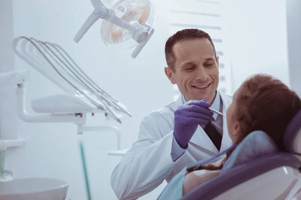 Exuberant male dentist scrutinizing teeth — Stock Photo, Image