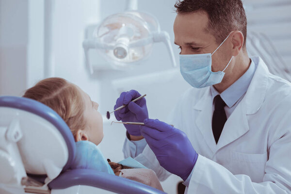 Опытный мужчина дантист с помощью стоматологического инструмента
