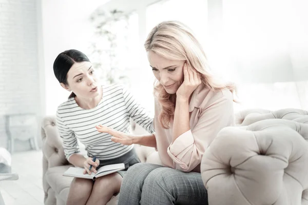 Annoyed sad woman touching to head and shaking another hand. — Stock Photo, Image