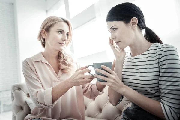 Angenehme freundliche Frau sitzt und gibt eine Tasse. — Stockfoto