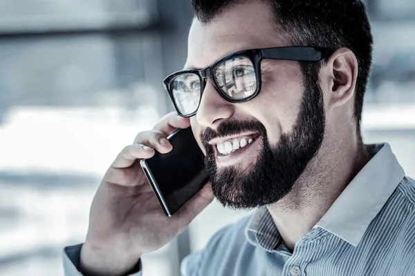 Удовлетворенный человек в очках с помощью мобильного телефона и улыбаясь . — стоковое фото