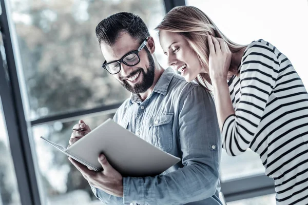 Felices colegas interesados sonriendo y con vistas a la carpeta . — Foto de Stock