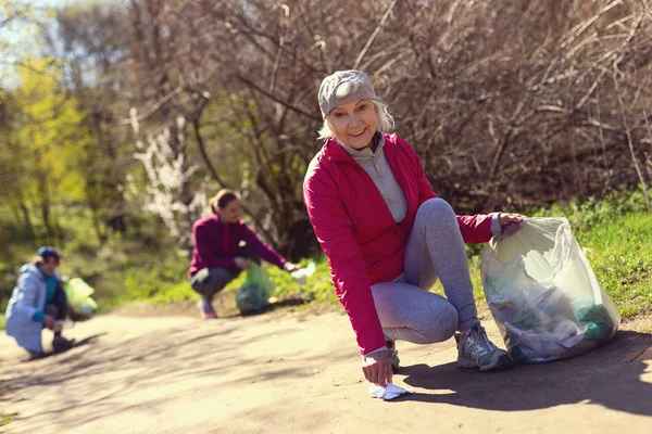 Mujer contenta recogiendo basura con sus amigos — Foto de Stock