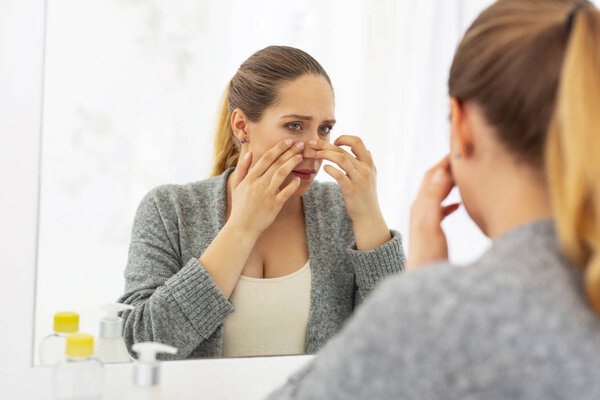 Attractive earnest woman squeezing out pimple