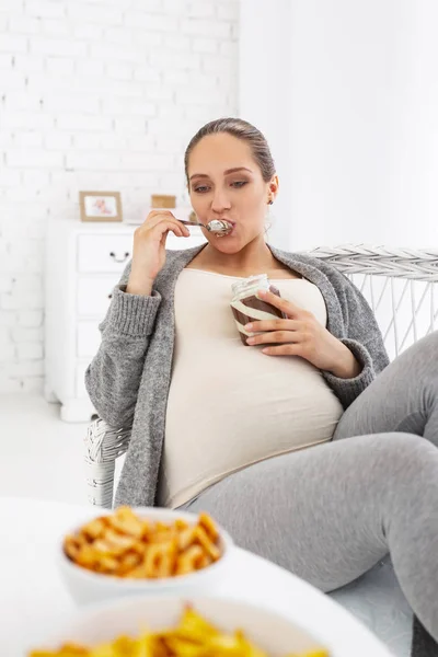 Sinnierende schwangere Frau leckt Kakaoaufstrich — Stockfoto