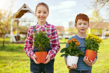 Bahçede. Güzel pozitif çocuk sana duran bahçede çiçek ile bakmak
