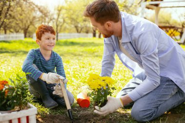 Olumlu ruh hali. Neşeli mutlu çocuk babasına onun ile bahçede çalışırken gülümseyen