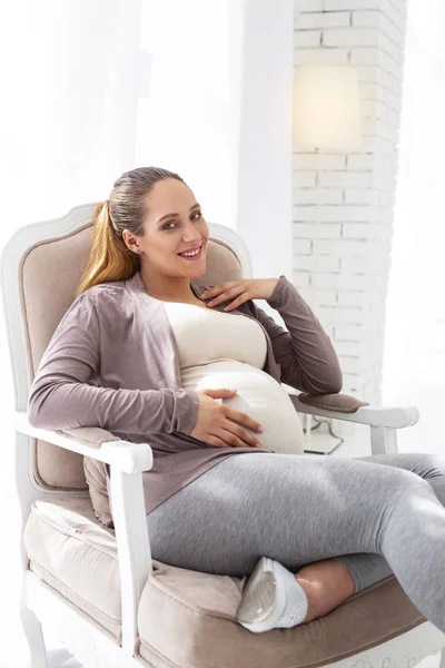 Mulher grávida positiva descansando na cadeira — Fotografia de Stock