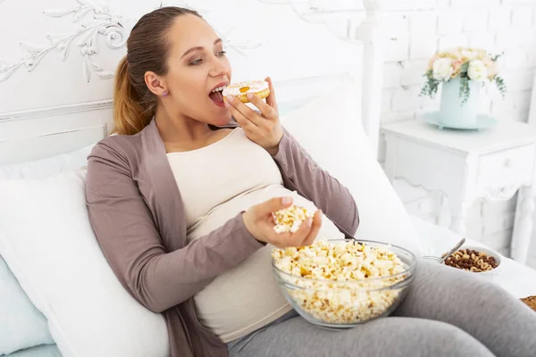 Merry pregnant woman biting French pastry — Stock Photo, Image