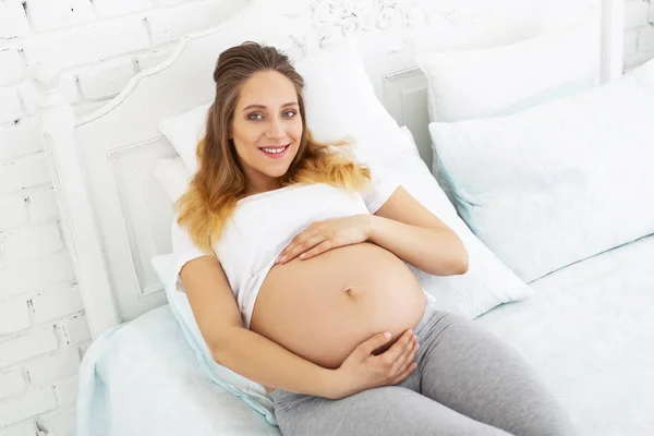 Veselá těhotná žena mazlení jí břicho — Stock fotografie