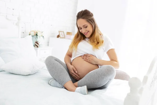 Mulher grávida feliz admirando barriga — Fotografia de Stock