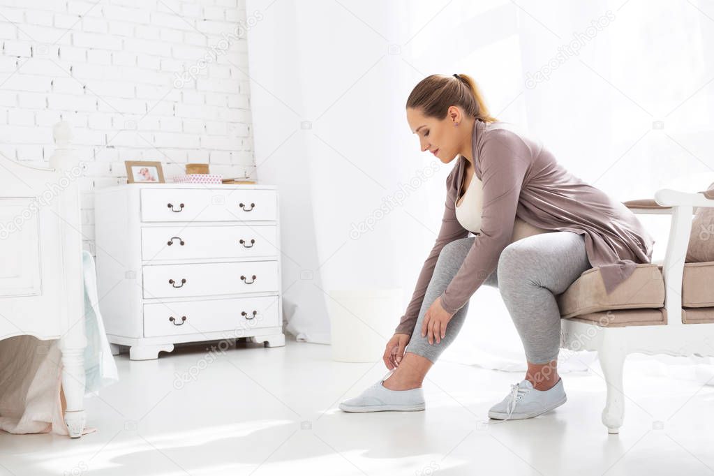 Beautiful pregnant woman tying laces