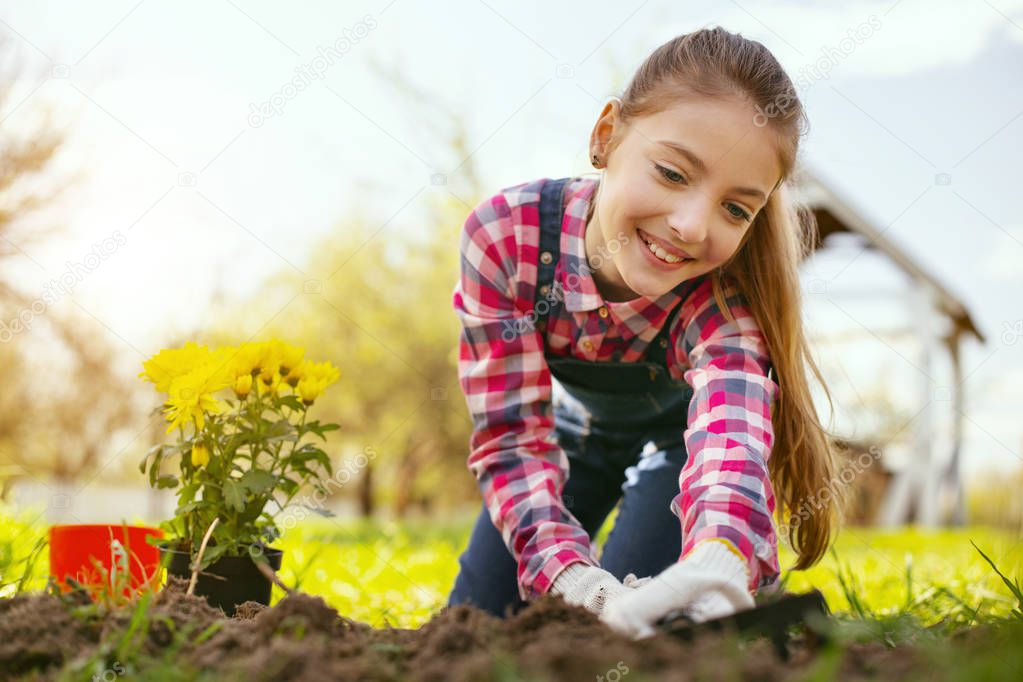 Joyful happy girl using gardening tools