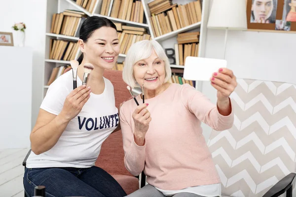 Gelukkig vrijwilligers en senior vrouw die lacht voor selfie — Stockfoto