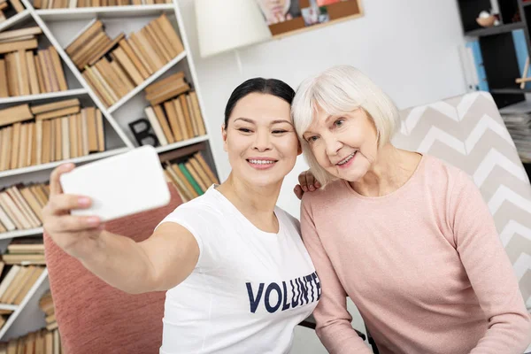 Radosny wolontariuszy i starszy kobieta biorąc selfie — Zdjęcie stockowe