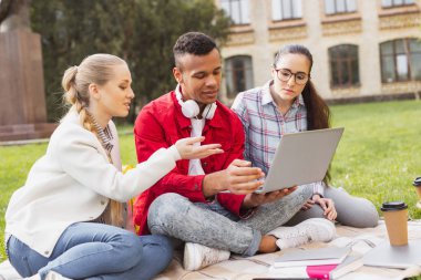 Üç millennials çimenlerin üzerinde otururken alışveriş online