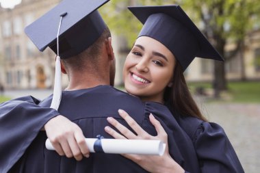 Gülümseyen mezunu sevgilisi sarılma kolej giyiyor