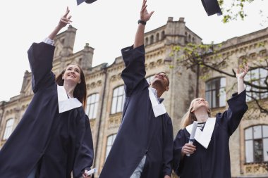 Hoş öğrenciler university yakınındaki havadaki mortarboards atma