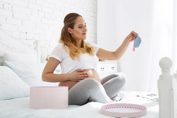 Очаровательная беременная женщина, изучающая носки — стоковое фото