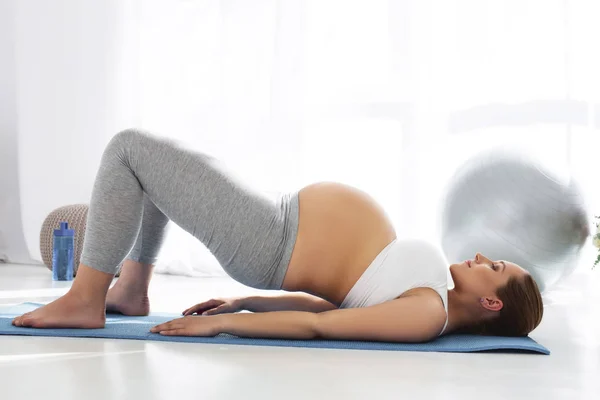 Fokuserade gravid kvinna utövar yoga — Stockfoto