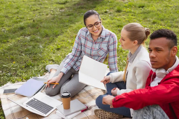 Okurken dizüstü kullanarak kare gömlek gülümseyen öğrenci