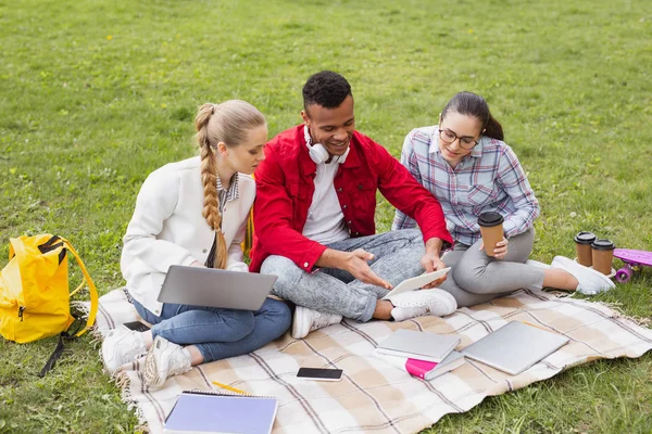 Drie knappe studenten zitten in het park in de buurt van Universiteit — Stockfoto