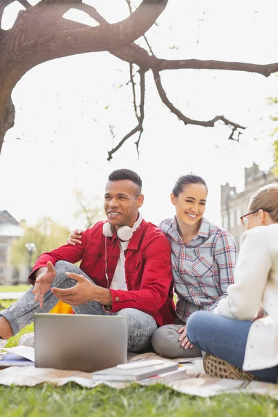 Un par de estudiantes sonrientes sentados bajo el árbol —  Fotos de Stock