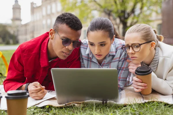 Drie studenten attente gevoel tijdens het kijken naar educatieve video — Stockfoto