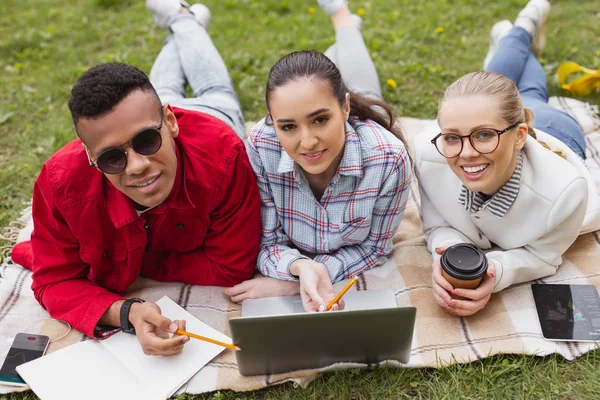 Three students wearing denim lying in the grass — Stock Photo, Image